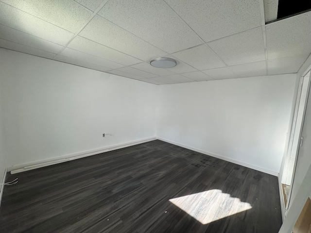 spare room with dark hardwood / wood-style floors and a drop ceiling