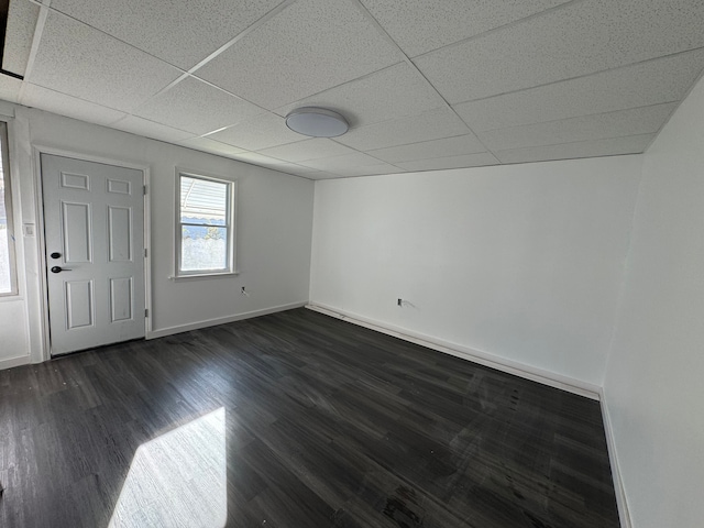 spare room featuring a paneled ceiling and dark hardwood / wood-style floors