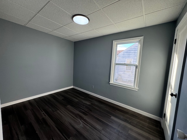 unfurnished room with dark hardwood / wood-style floors and a drop ceiling