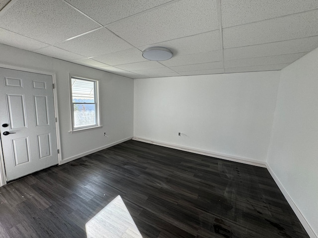 empty room with dark hardwood / wood-style flooring and a drop ceiling