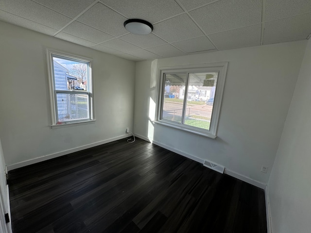 spare room featuring dark hardwood / wood-style floors and a drop ceiling