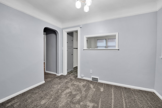 unfurnished room featuring baseboards, visible vents, dark colored carpet, and arched walkways