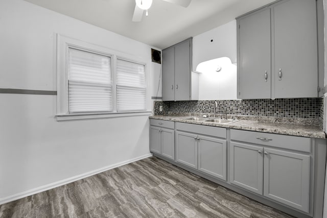 kitchen featuring tasteful backsplash, light countertops, a sink, and gray cabinetry