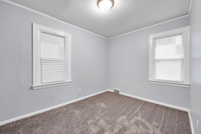 carpeted empty room with baseboards, visible vents, and crown molding