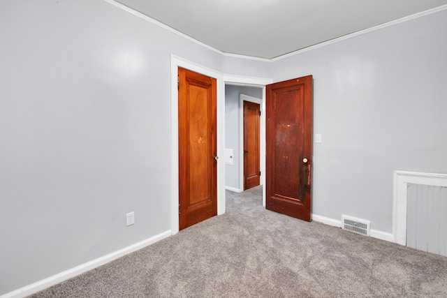 unfurnished room with carpet, visible vents, crown molding, and baseboards