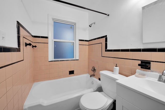 full bath with toilet, a wainscoted wall, vanity, shower / washtub combination, and tile walls