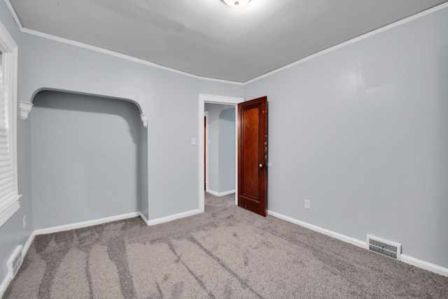 spare room featuring light colored carpet, visible vents, crown molding, and baseboards