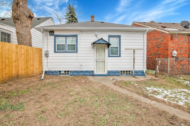 rear view of house featuring fence and roof with shingles