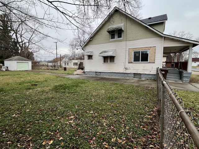 back of house featuring a lawn, a garage, and an outdoor structure