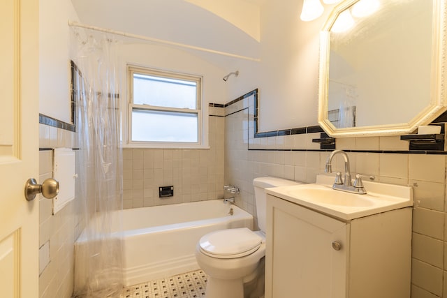 full bathroom with tile patterned flooring, toilet, shower / bath combo with shower curtain, vanity, and tile walls