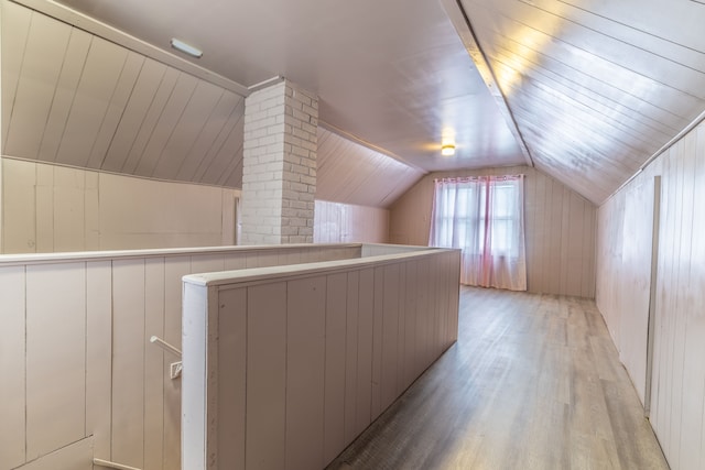 bonus room featuring light hardwood / wood-style flooring, vaulted ceiling, and wood walls