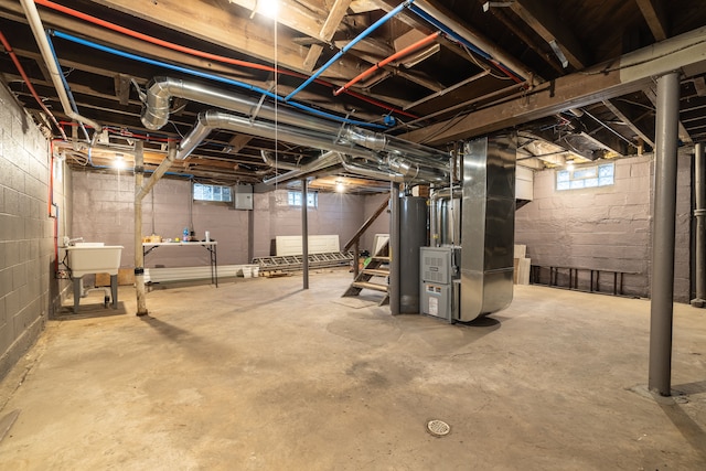 basement featuring heating unit, water heater, and sink