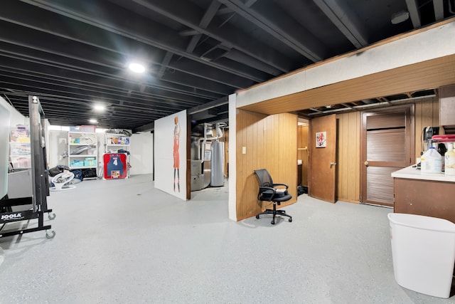 basement featuring wooden walls and water heater