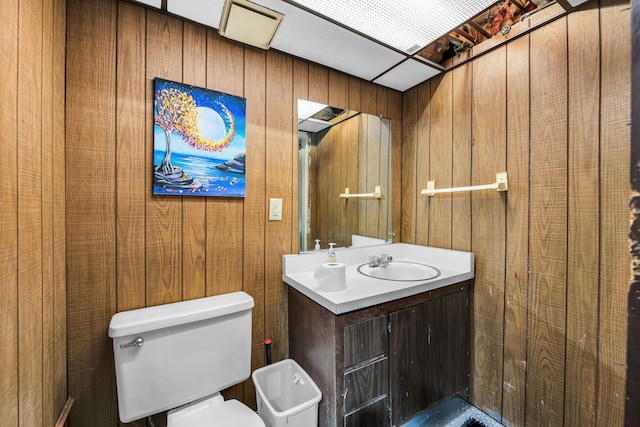 bathroom featuring vanity, wood walls, and toilet