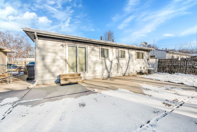 snow covered rear of property featuring a patio area and central air condition unit