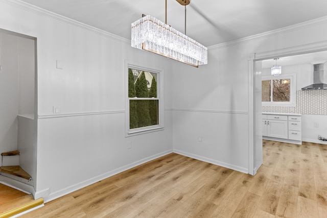 unfurnished dining area with light hardwood / wood-style floors, crown molding, and a chandelier