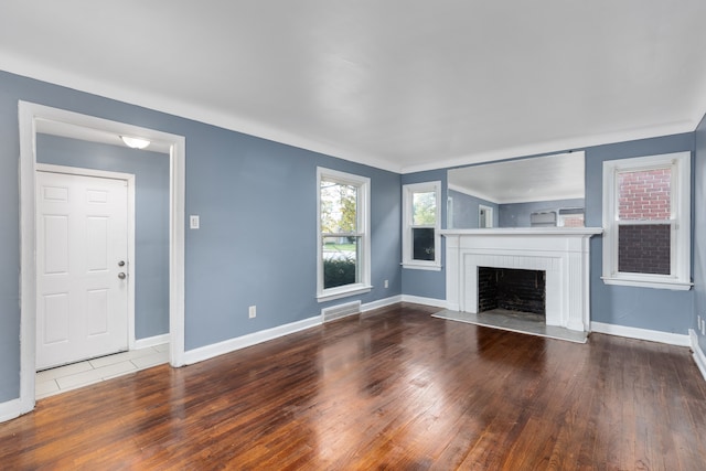 unfurnished living room featuring wood-type flooring and a brick fireplace