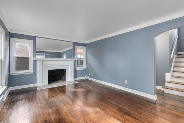 unfurnished living room with dark hardwood / wood-style flooring and a brick fireplace