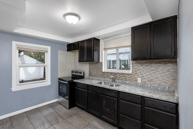 kitchen featuring light stone countertops, sink, a raised ceiling, decorative backsplash, and stainless steel range with electric cooktop