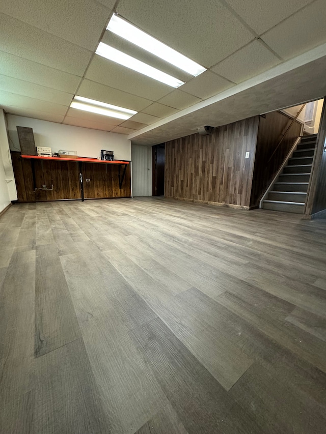 basement featuring a paneled ceiling and wood walls