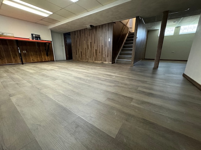 basement featuring a paneled ceiling and wooden walls