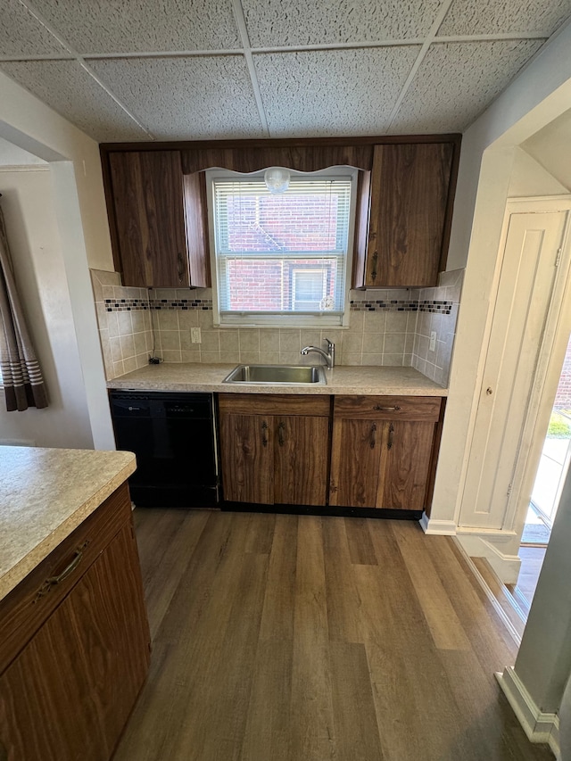 kitchen with black dishwasher, hardwood / wood-style floors, a paneled ceiling, and decorative backsplash