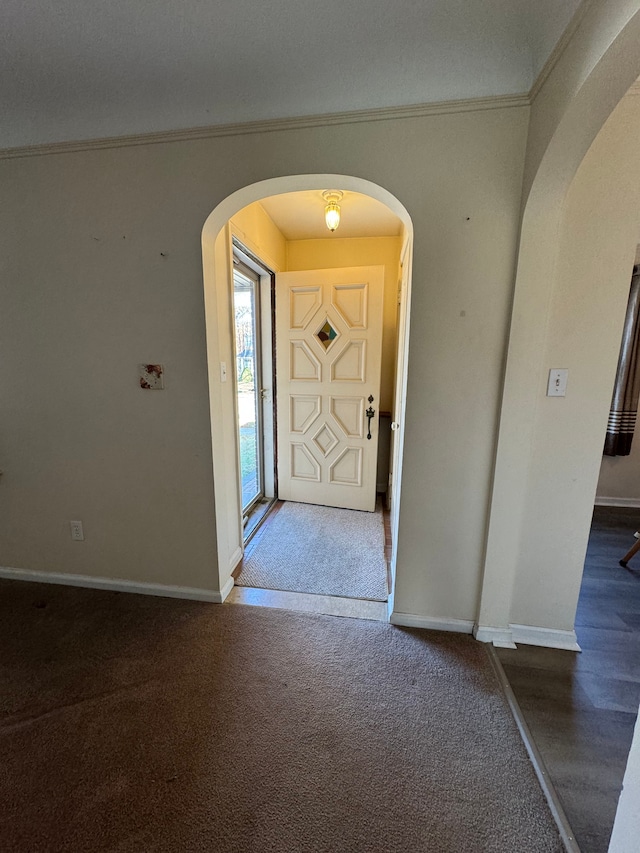 entrance foyer with dark carpet and crown molding