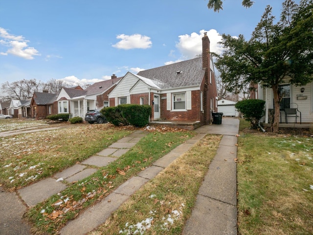 bungalow-style home with a garage, an outdoor structure, and a front yard