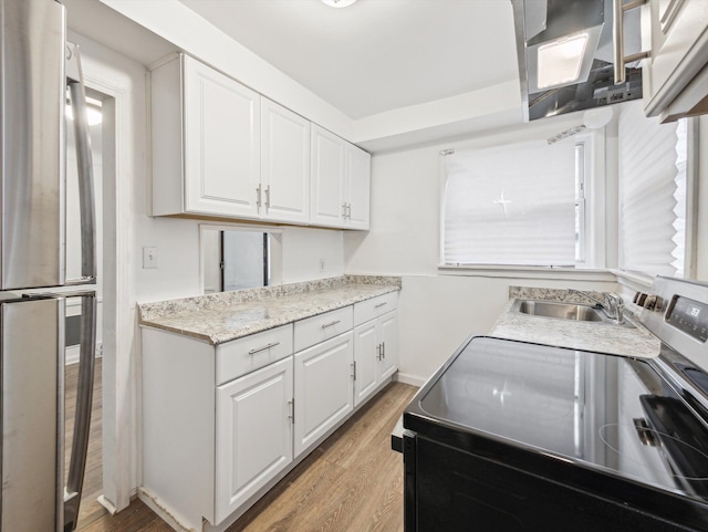 kitchen with white cabinetry, sink, stainless steel fridge, and electric stove