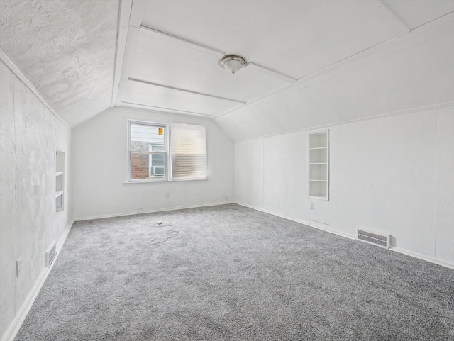 bonus room with built in shelves, vaulted ceiling, and carpet flooring