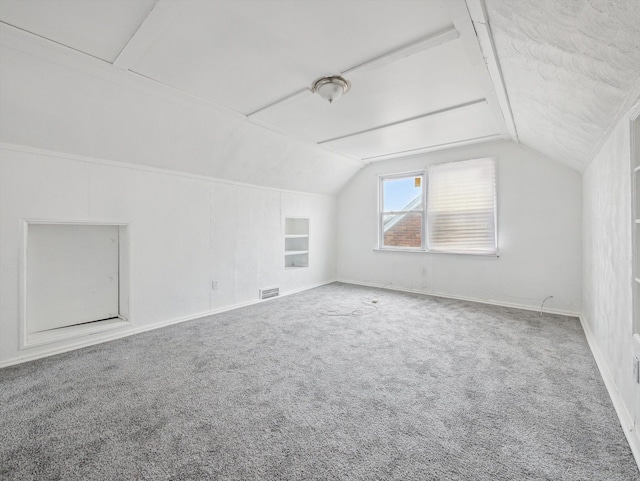 additional living space featuring built in shelves, carpet flooring, and vaulted ceiling