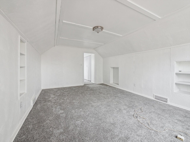 additional living space featuring vaulted ceiling, built in features, and carpet flooring