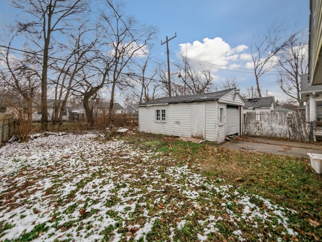 yard covered in snow featuring a garage and an outbuilding