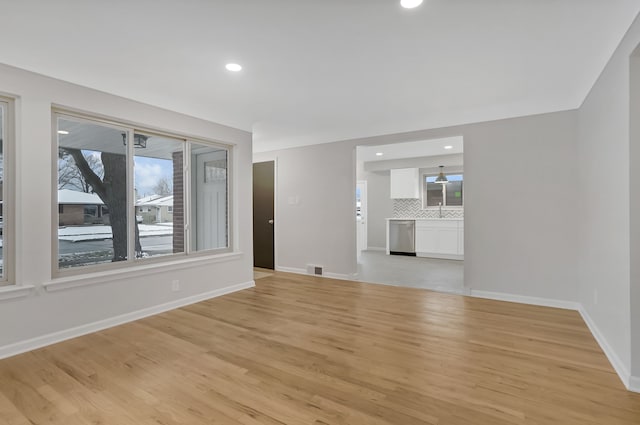 unfurnished living room with sink and light hardwood / wood-style floors