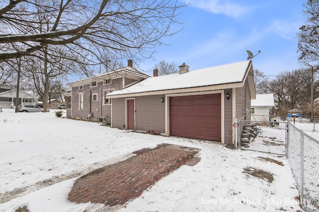 snow covered garage featuring fence