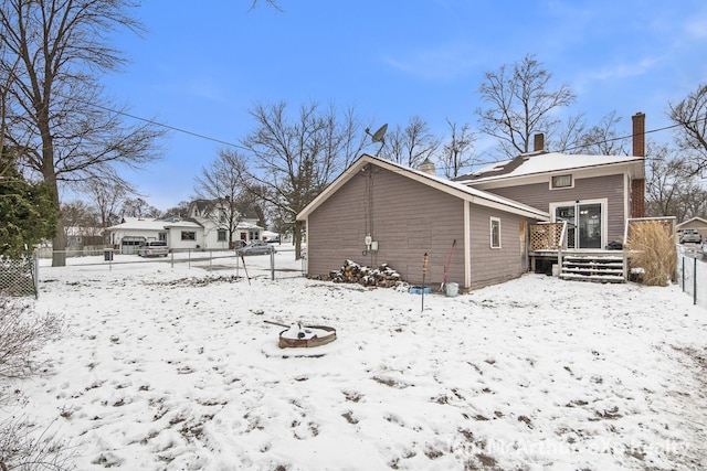 snow covered property with a deck and fence