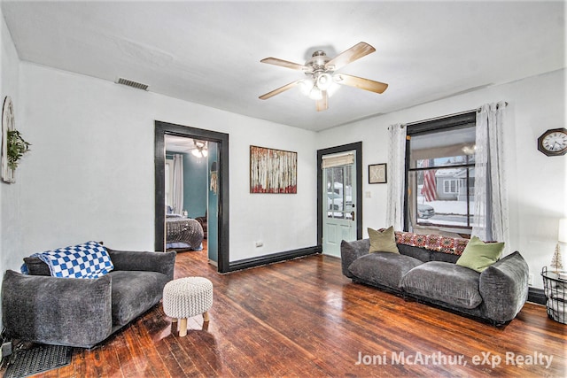 living area with visible vents, baseboards, wood finished floors, and a ceiling fan