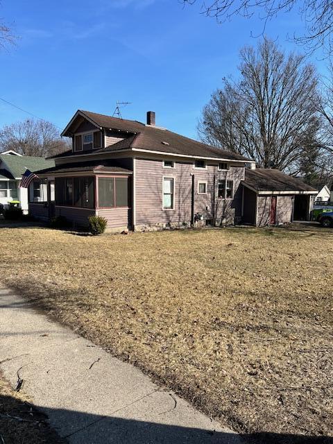 exterior space featuring a chimney, a yard, and a sunroom