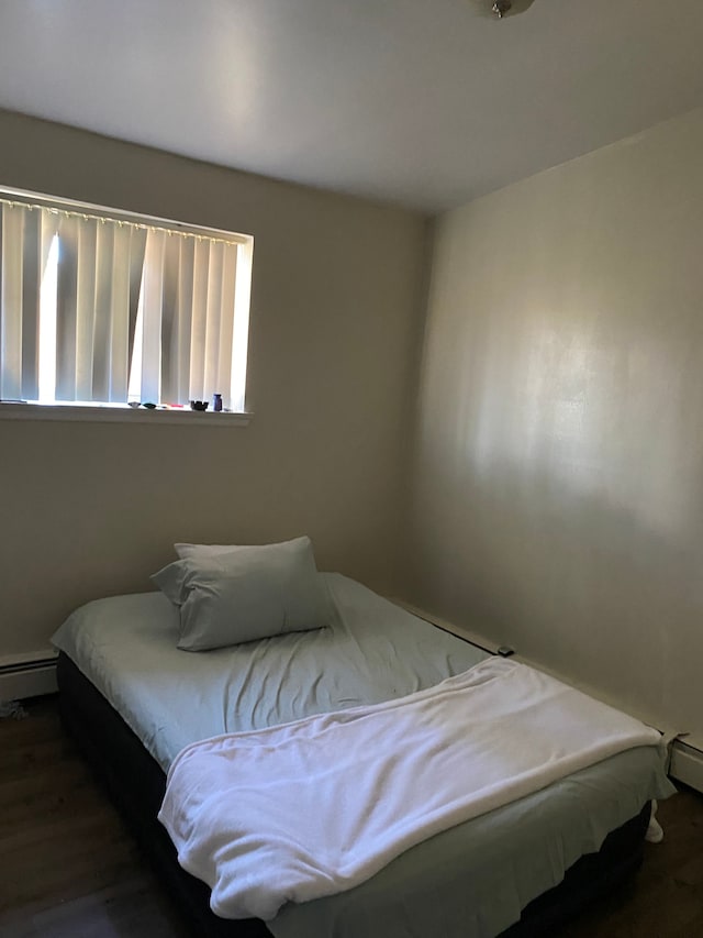 bedroom with baseboard heating and dark wood-type flooring