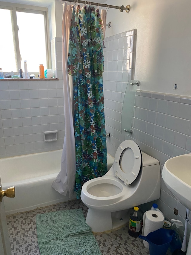 bathroom with tile patterned floors, toilet, shower / bathtub combination with curtain, and tile walls