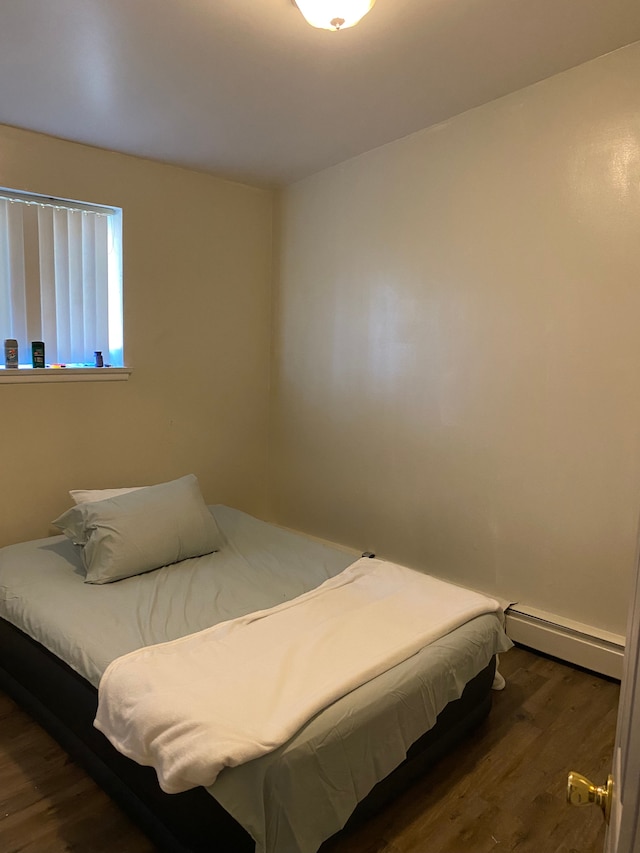 bedroom with baseboard heating and dark hardwood / wood-style floors