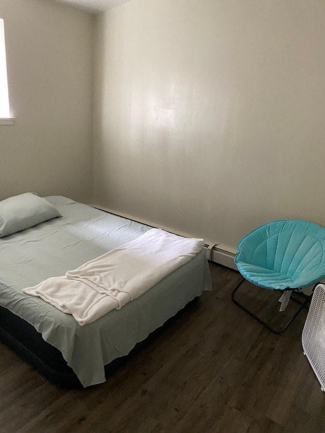 bedroom with a baseboard radiator and dark hardwood / wood-style floors