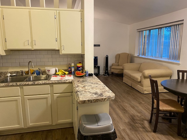 kitchen featuring dark wood-type flooring, white cabinets, sink, decorative backsplash, and light stone countertops