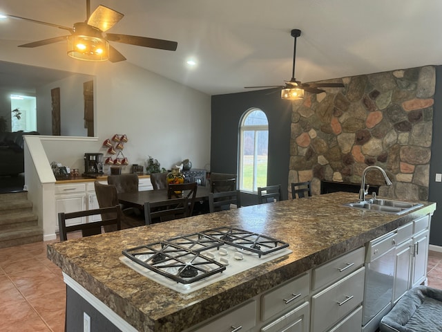 kitchen with gas cooktop, light tile patterned flooring, sink, dishwasher, and an island with sink