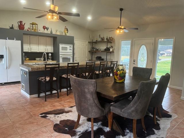 tiled dining space with ceiling fan, lofted ceiling, and sink