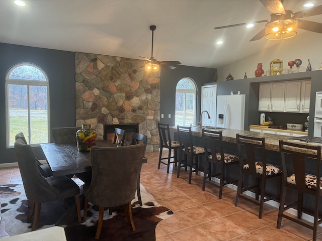 dining room featuring a fireplace, sink, lofted ceiling, and light tile patterned flooring