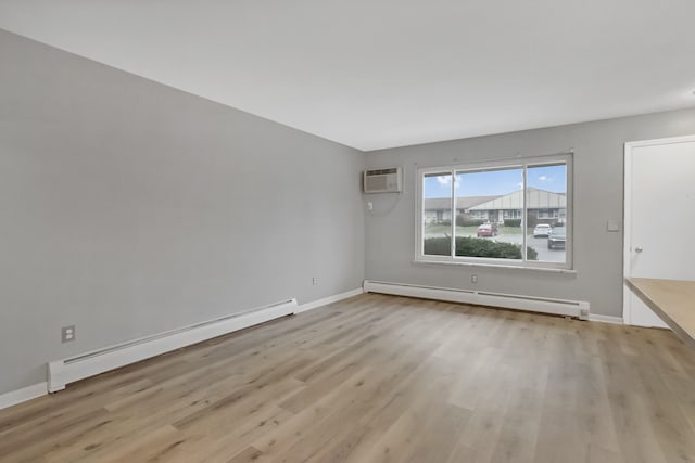 empty room featuring light wood-type flooring, an AC wall unit, and baseboard heating