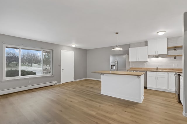 kitchen with appliances with stainless steel finishes, backsplash, white cabinets, butcher block countertops, and hanging light fixtures