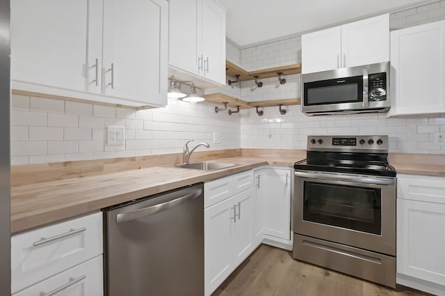 kitchen featuring white cabinets, wood counters, appliances with stainless steel finishes, and tasteful backsplash