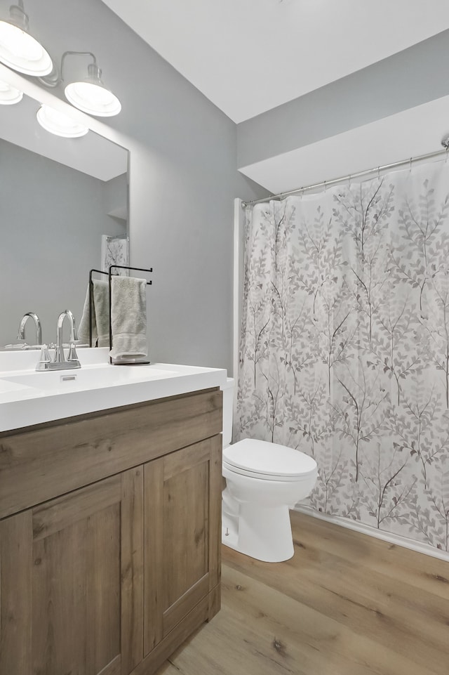 bathroom featuring hardwood / wood-style floors, vanity, toilet, and walk in shower